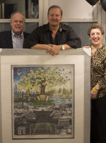 Charles Fazzino at ArtsFest standing with two people in behind one of his pieces of work.