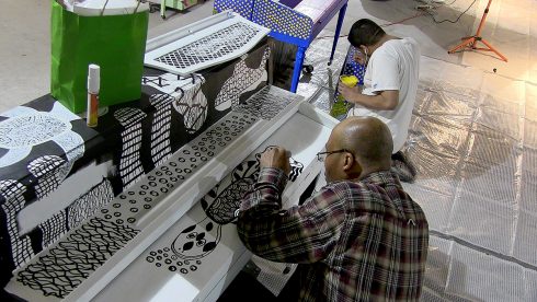 Cory Tyler and Jayson Valles paint murals onto their pianos in the studio.