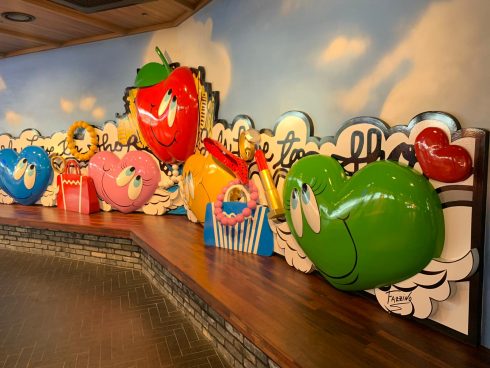 A colorful Fazzino installation behind a long bench at the mall showcasing classic Fazzino smiling hearts and an apple.