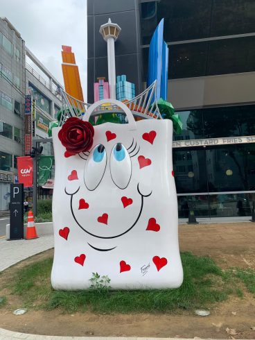 Large smiliing shopping bag installation by Charles Fazzino