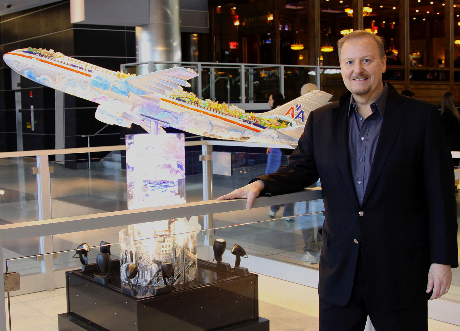 Fazzino standing next to his airplane piece at JFK Airport.