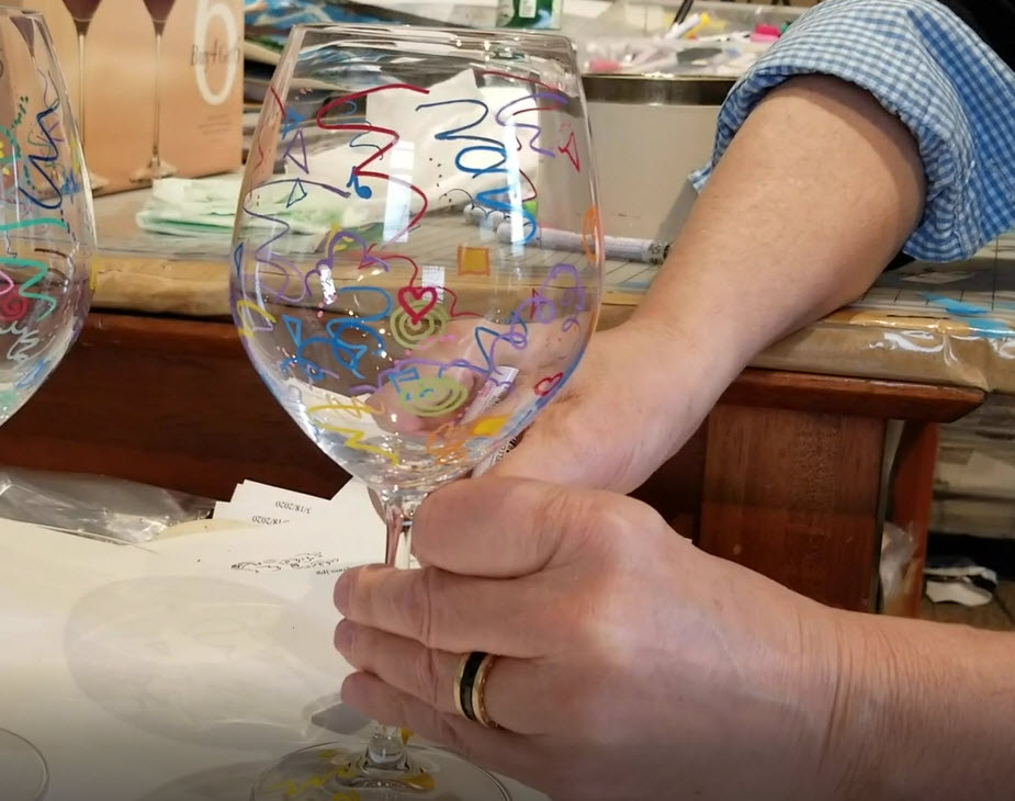 Fazzino demonstrates how to draw on a wine glass with permanent markers