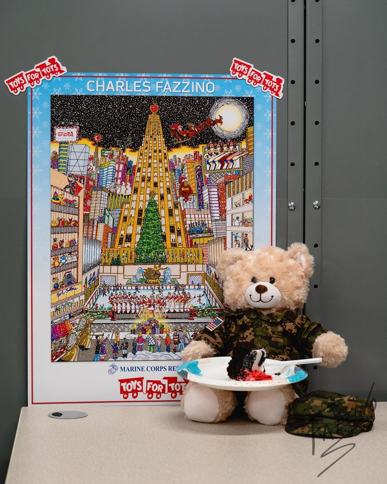 Toys for Tots poster by Charles Fazzino next to a stuffed bear eating a slice of cake.