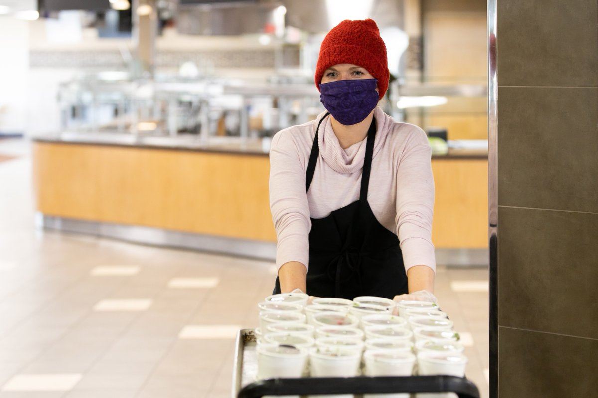 woman wearing mask pushing a cart for meals on wheels