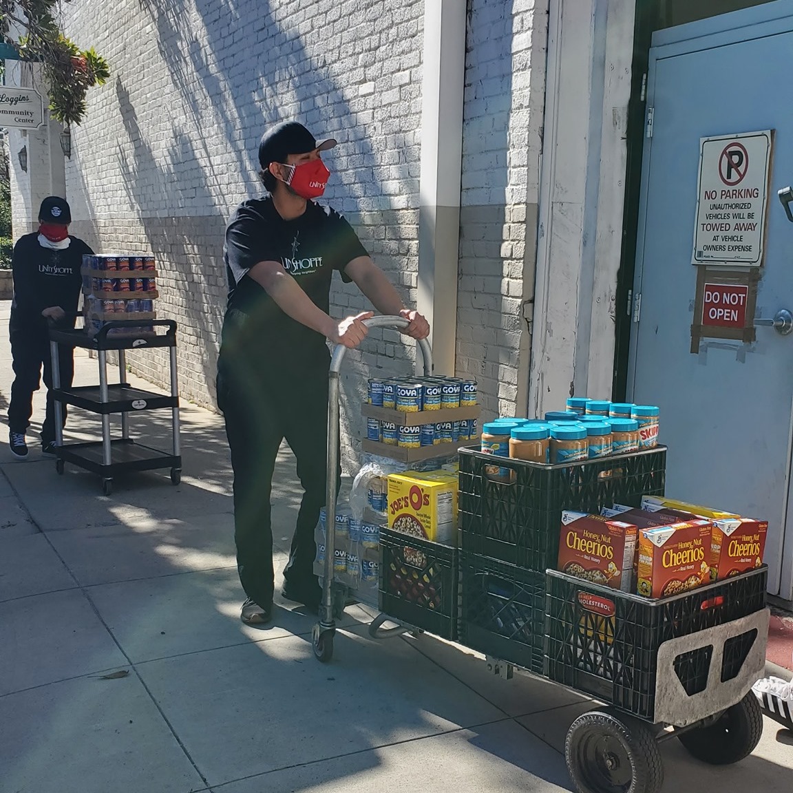 young man pushing a cart of food into building - Unity Shoppe