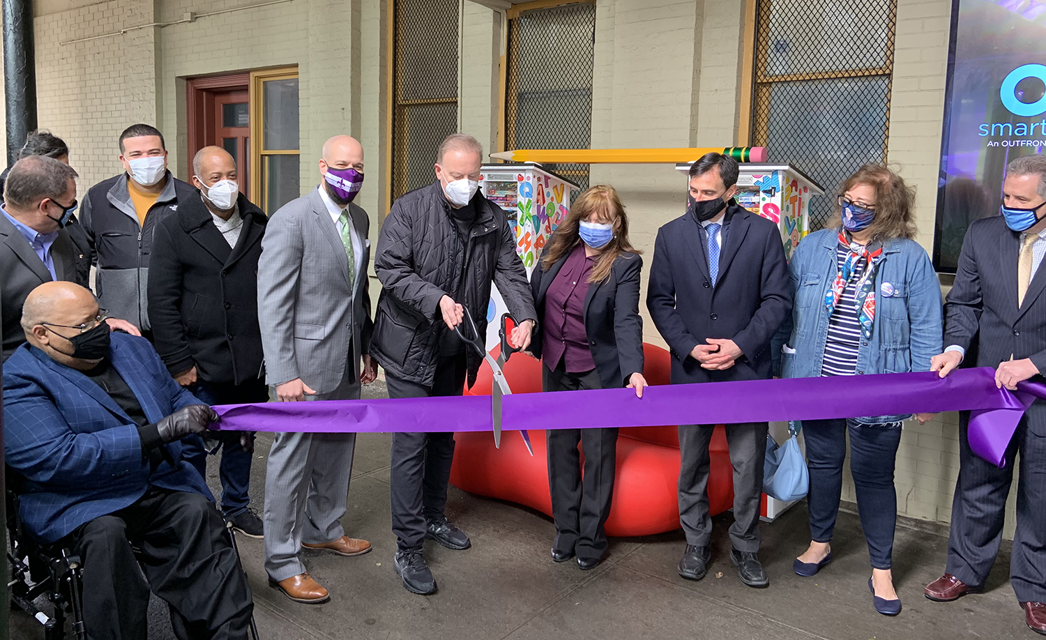 Charles Fazzino with city officials cutting a purple ribbon down at the New Rochelle Train station celebrating his new art installation 