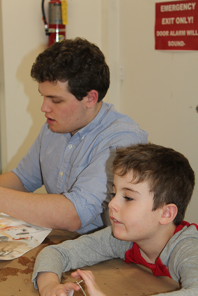 2021 Fazzino Award of Heart winner Andrew Terraciano sitting at a table doing crafts with a young boy