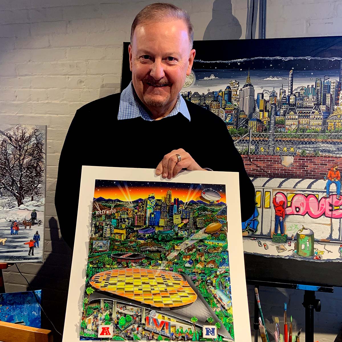 Pop art artist Charles Fazzino smiling and holding the Super Bowl LVI: Los Angeles Poster in his gallery