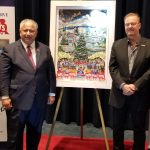 Charles Fazzino and SECNAV Del Toro stand on either side of the Toys for Tots 75th anniversary art piece, which features a Christmas tree surrounded by carolers and buildings from DC and NYC