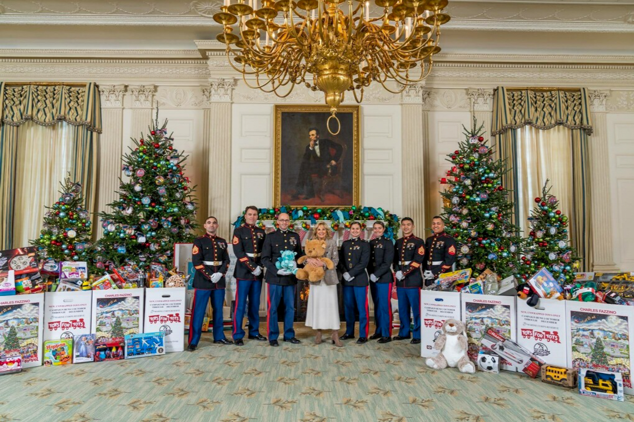 Members of the US Marines stand on either side of First Lady Dr. Jill Biden, surrounded by toys for tots donations at the white house