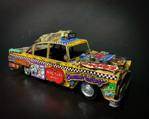 Side view of a car sculpture covered in Broadway elements.