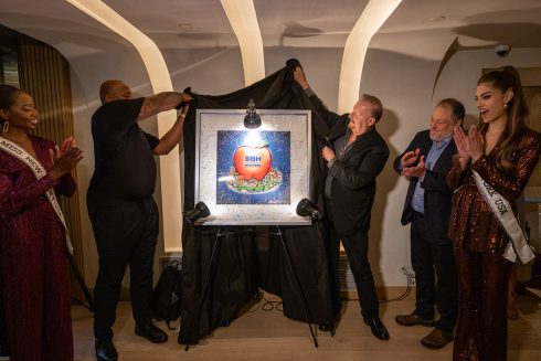 Charles Fazzino and NY Giants defensive star Dexter Lawrence pull back the curtain to unveil the artwork for the Team of Heroes gala kickoff while onlookers applaud and cheer