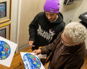 Two visitors to the Fazzino studio look at a piece of artwork 