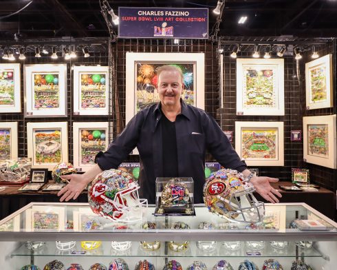 Charles spreads his arms out to show off his hand-painted helmet collection for Super Bowl LVIII