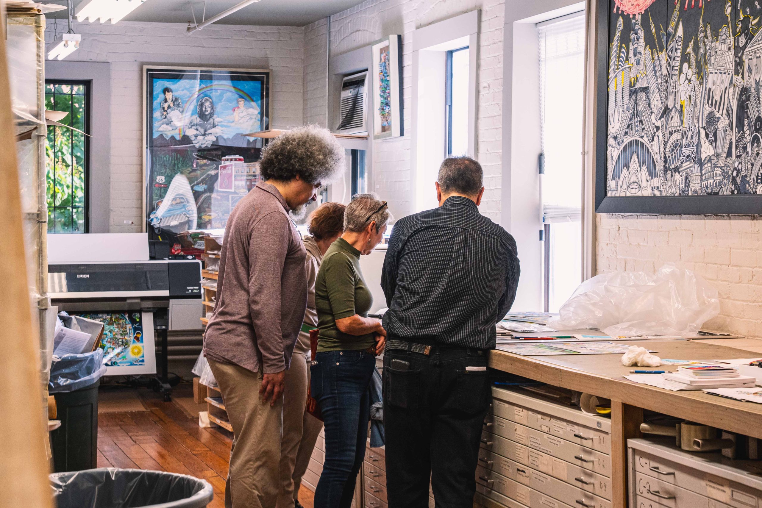 People look on at the printing process at the Fazzino studio