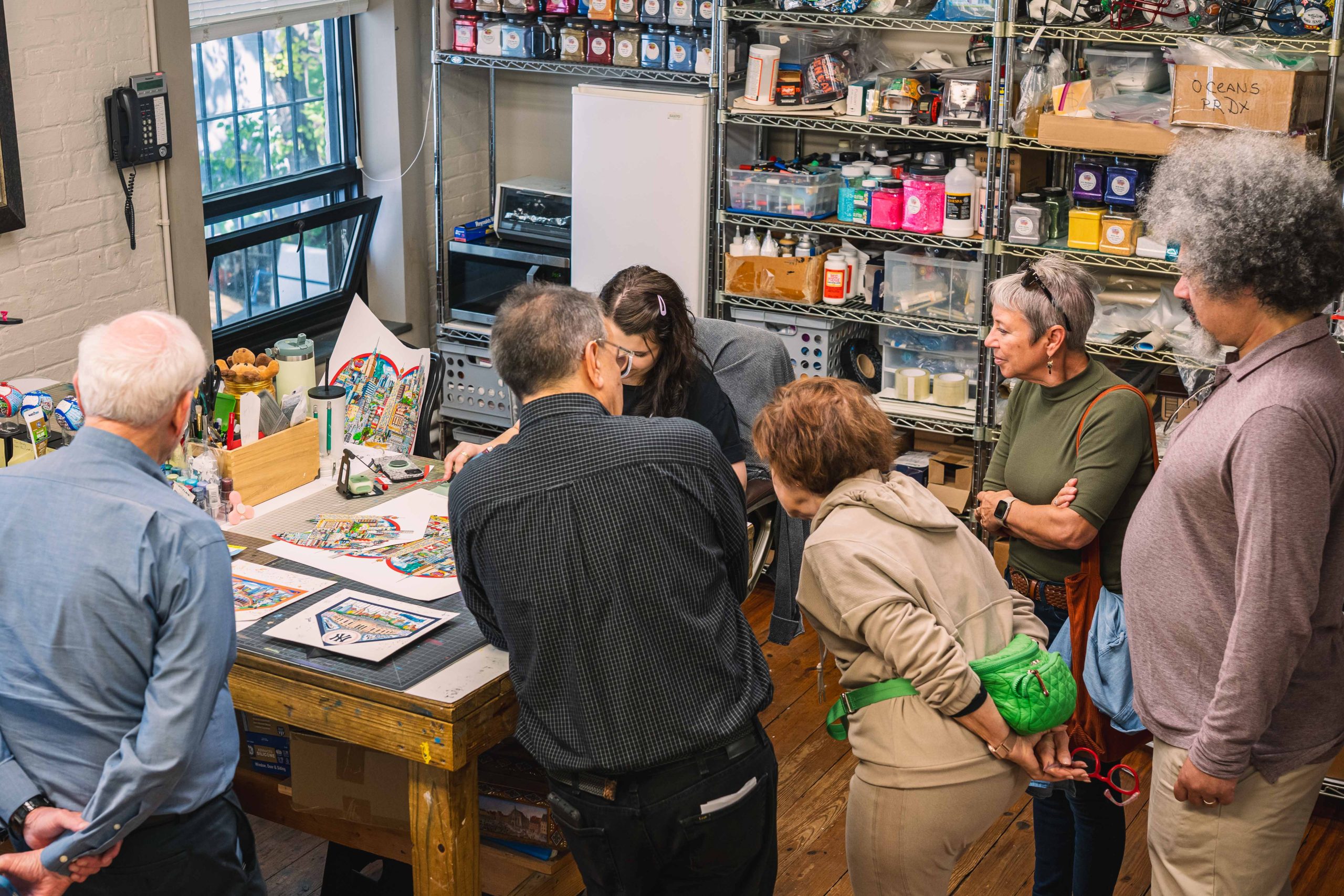 People gather around the table at the Fazzino studio to learn about the process that goes into making his 3d pop art